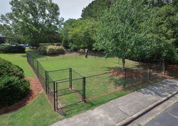 a fenced in area in a park with trees